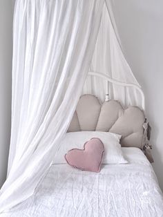 a white bed with a pink heart pillow on it