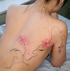 the back of a woman's shoulder with pink flowers on her left and right side