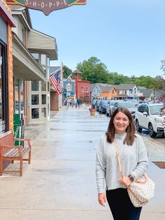 a woman walking down the sidewalk in front of a store