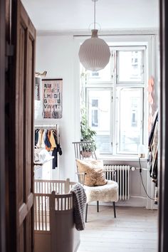 an open door leading to a bedroom with a chair and clothes hanging on the wall