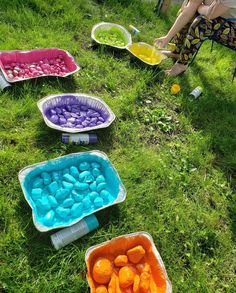 some people are sitting in the grass with their bowls full of different colored food items