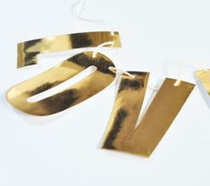 two pieces of gold colored metal on a white surface