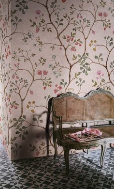 a bench sitting in front of a wallpapered room with pink flowers on it