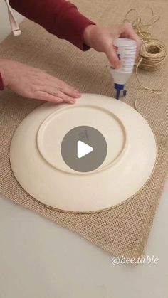 a person is making a craft project with paper plates and twine spools