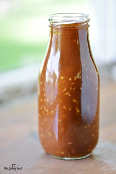 a jar filled with sauce sitting on top of a wooden table