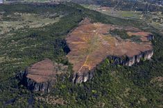 an aerial view of a mountain with trees and land