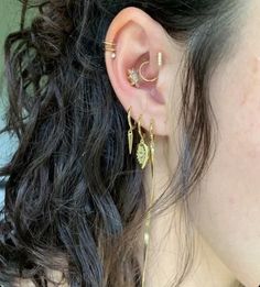 a close up of a person with ear piercings on their ears and wearing gold jewelry