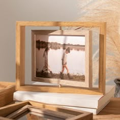 a wooden frame with two people walking in the water and one is holding a book