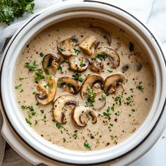 a white bowl filled with mushroom soup and garnished with parsley