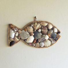 a fish made out of sea shells hanging on a wall