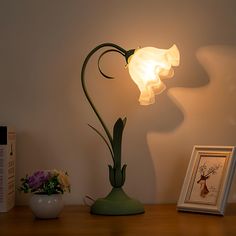 a lamp that is on top of a table next to a vase with flowers in it