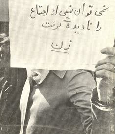 a man holding up a sign with writing on it in front of him and wearing a suit