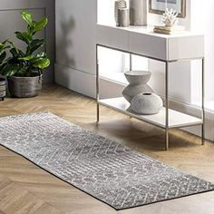 a living room with white walls and wooden floors, a rug on the floor and two vases