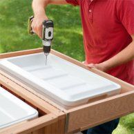 a man holding a drill in front of a white tray on top of a wooden table