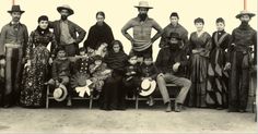 a group of people are posing for a photo with hats on their heads and one man is wearing a cowboy hat