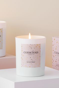 three candles are sitting next to each other on a white surface with gold confetti