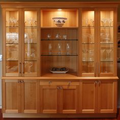 a wooden china cabinet with glass doors on the top and bottom, filled with wine glasses