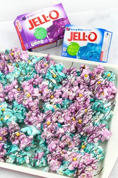 a tray filled with jello and candy next to a box of jello on top of a table