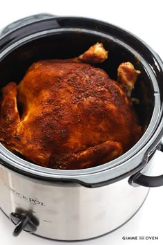 a close up of a cooked chicken in a crock pot on a white surface