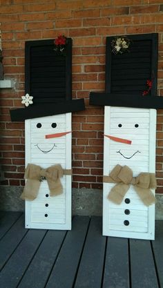 two snowmen made out of shutters sitting on top of a wooden floor next to a brick wall