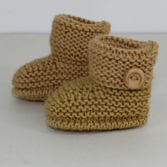 there is a pair of knitted baby boots with buttons on the front and bottom