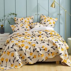 a bed with yellow flowers on it in a blue room next to a white dresser