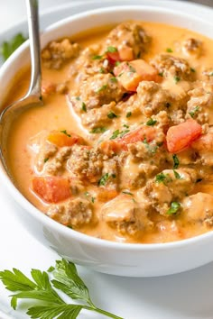 a white bowl filled with meat and vegetable soup on top of a plate next to a spoon