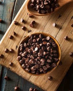 two wooden spoons filled with chocolate chips on top of a cutting board - stock photo - images