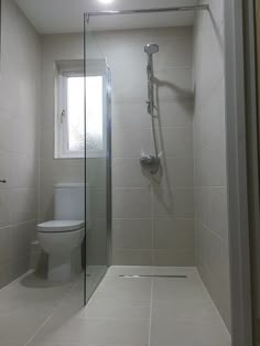 a bathroom with a toilet, shower and glass door on the wall next to it