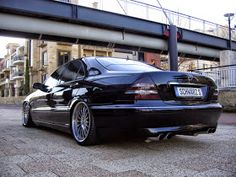 a black car parked in front of a bridge