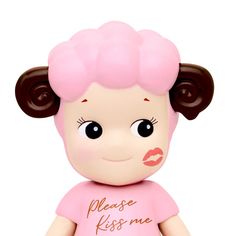 a small doll with brown hair and pink shirt on it's head, has the words please kiss me written on her face