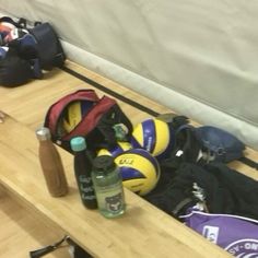 sports equipment sitting on the floor next to a table with water bottles and backpacks