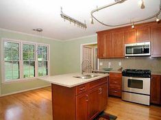 an empty kitchen with wood floors and stainless steel appliances