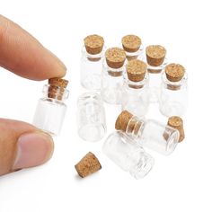 small glass bottles with corks are being held by a finger