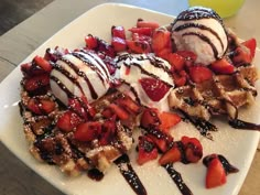 waffles with strawberries and chocolate drizzled over them on a white plate