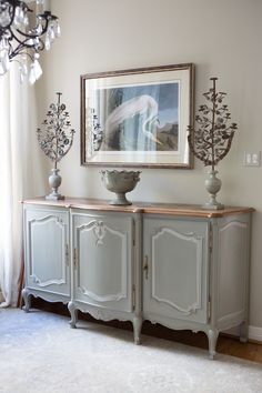 an ornate sideboard with two vases and a painting on the wall