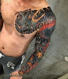 a man with a dragon tattoo on his arm and chest standing next to a wall