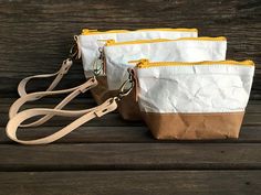 three purses sitting on top of a wooden table next to each other with straps