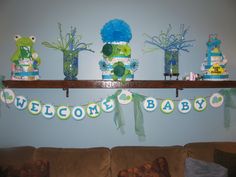 a welcome baby banner is hanging on the wall above a couch with teddy bears and other decorations