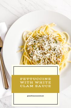 fettuccini with white clam sauce on a plate next to silverware