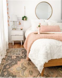 a bedroom with a bed, mirror and rug on the floor in front of it