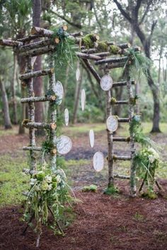 an arch made out of branches with white plates and greenery hanging from it's sides