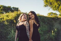 two beautiful women standing next to each other in front of some trees and bushes smiling