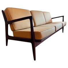 a brown and tan couch sitting on top of a wooden frame with armrests