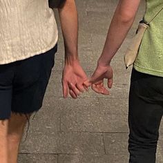 two people standing next to each other holding hands