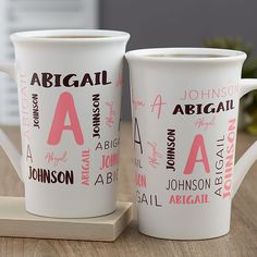 two personalized coffee mugs sitting on a wooden tray with the names of different cities