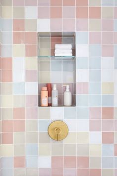 a bathroom with pink and blue tiles on the wall, toiletries and soaps