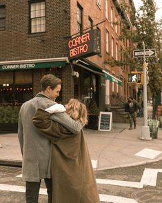 a man and woman crossing the street in front of a corner bistro