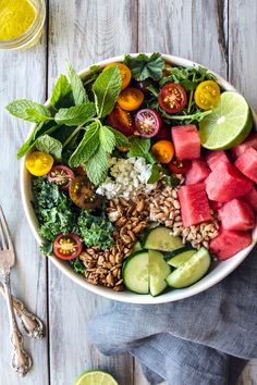 two bowls filled with watermelon, cucumber, and other food items