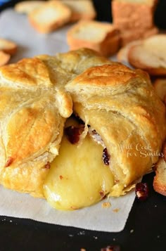 a cranberry and cheese pastry is shown with crackers around it on a black surface